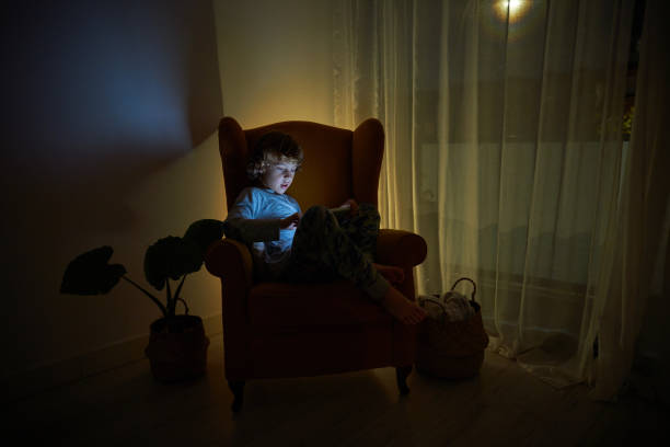 istock Boy playing on tablet in dark room 2167959741