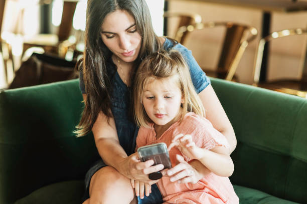 istock Mother using a cellphone at home on the couch with young daughter 2167962152