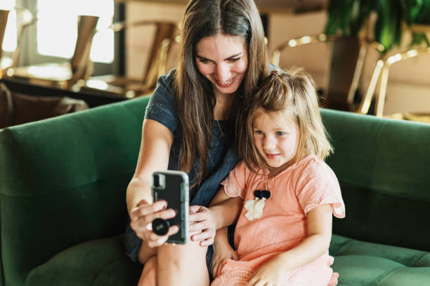 istock Mother using a cellphone at home on the couch with young daughter 2167962170