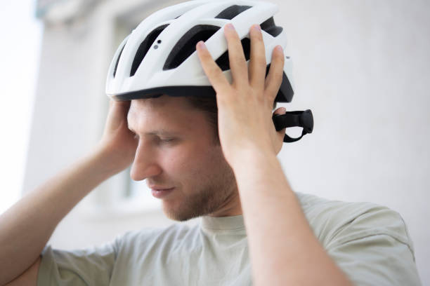 istock A man adjusts and puts on his white helmet while standing next to his bicycle in a park 2167967746