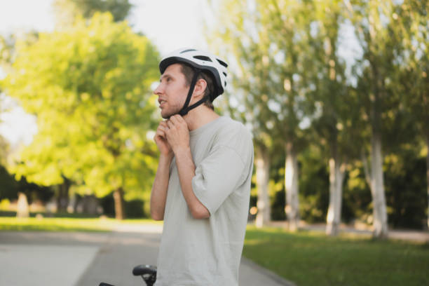 istock A man adjusts and puts on his white helmet while standing next to his bicycle in a park 2167967747
