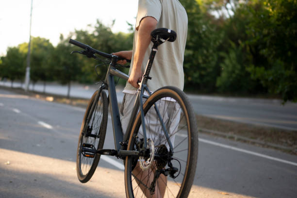 istock man walks on a paved path in a park, carrying a black bicycle over his shoulder 2167967967