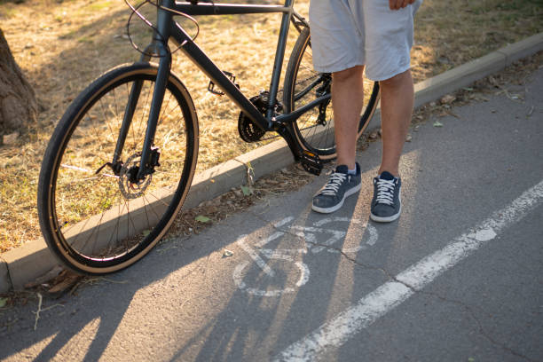 istock A person stands beside their bicycle on a bike path, with a white line separating the path from the sidewalk. environmentally friendly transport concept 2167967970