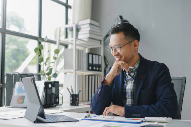 istock Accountant is smiling while working on his tablet and analyzing graphs and charts in his office 2167985078