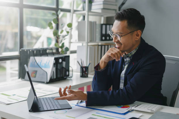 istock Businessman is using a tablet for a video conference while sitting at his desk in an office 2167985081