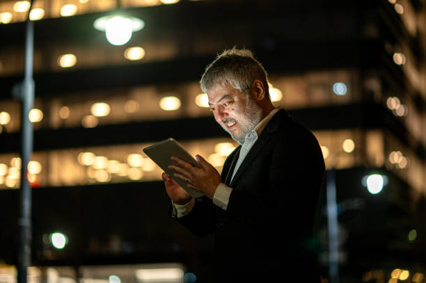 istock Man using cell phone and tablet at night outside the office 2167986718