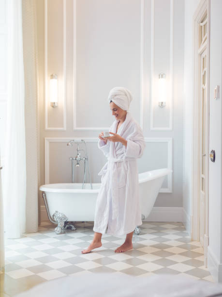 istock Happy woman in bathrobe with coffee in bathroom 2167992326