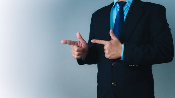 istock Businessman standing with finger pointing sideways to indicate selection or display of product in advertisement, product and service advertisement, marketing strategy. 2167995344