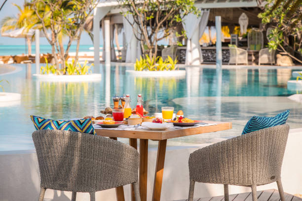 Maldives breakfast table by the pool under palm trees with scenic views on idyllic vacation island luxury resort