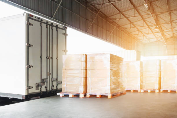 istock Bulk Pallets of Package Boxes Wrapped Plastic Stacked on Pallets. Trucks Loading at Warehouse Dock. Distribution Warehouse Shipping, Supply Chain Supplies, Shipment. Freight Truck Logistics Transport. 2167996231