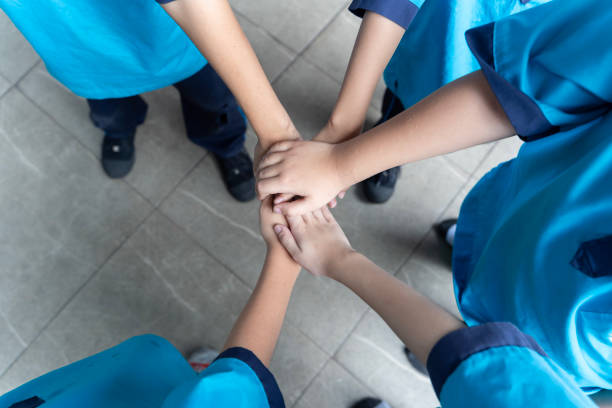 Little children holding hands together indoors. Unity concept. Closeup of adult and children stacking hands together outside.