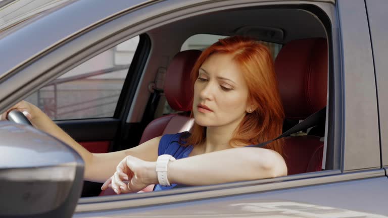 Impatient pretty mature woman driver checking time at wristwatch in rush hour
