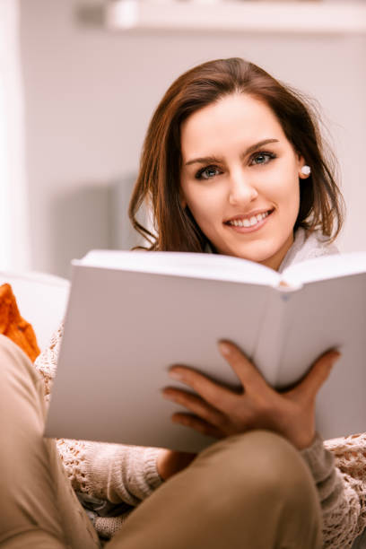istock Beautiful woman relaxing on sofa reading a book at home 2167999749