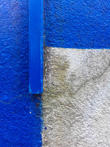 istock Concrete wall with wooden beam partially painted blue. Cracks and rough surface are visible 2168000915