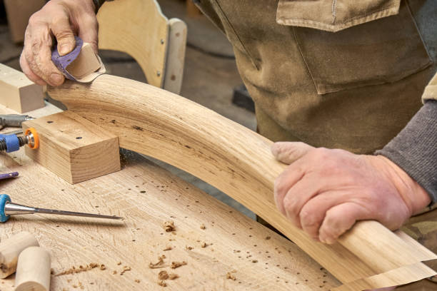 istock Carpenter sands bending wooden railing in workshop 2168008085