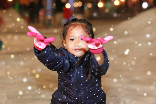 istock Happy little Asian child girl wearing a red jacket has a fun in snow, Winter time. 2168009891