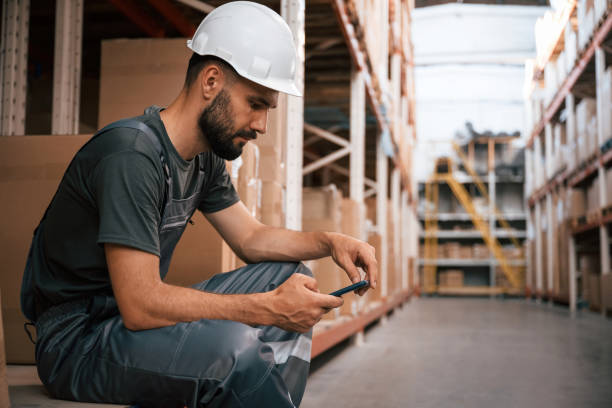 istock Taking a break, sitting with smartphone. Foreman is in the storehouse, shipping distribution business 2168010650