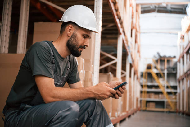 istock Taking a break, sitting with smartphone. Foreman is in the storehouse, shipping distribution business 2168010652