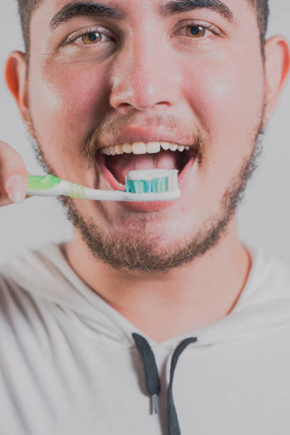 istock Smiling man brushing teeth isolated. Health and tooth brushing concept 2168011315