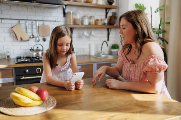 istock Woman talking to daughter using smartphone in kitchen at home 2168012933