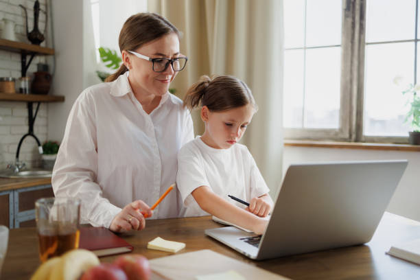 istock Smiling mother supporting daughter with online education in kitchen 2168013198