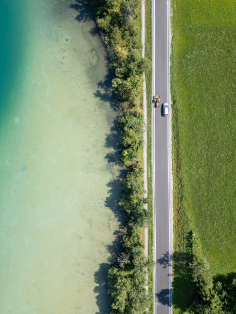 istock Top-Down View of Car and Tractor on Lakeside Road 2168015557