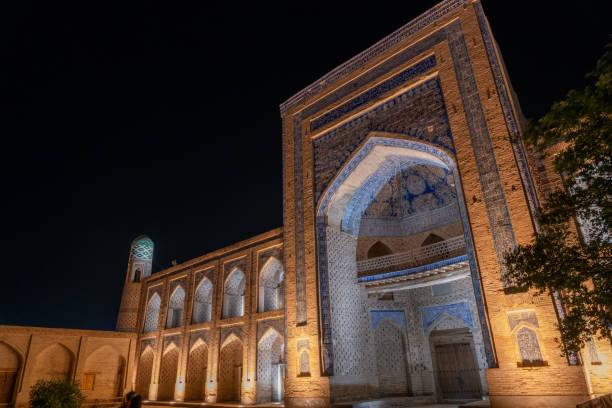 istock A large building with a blue archway and a clock tower. The building is lit up at night 2168020424