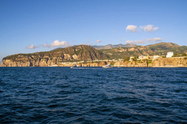 A breathtaking panoramic view of Sorrento's coastline at dawn, with the sun casting a golden glow on the cliffs and the calm sea.