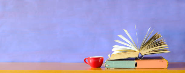 Open book with purple  background and cup of coffee: Reading, learning, education or home office concept.Free copy space.