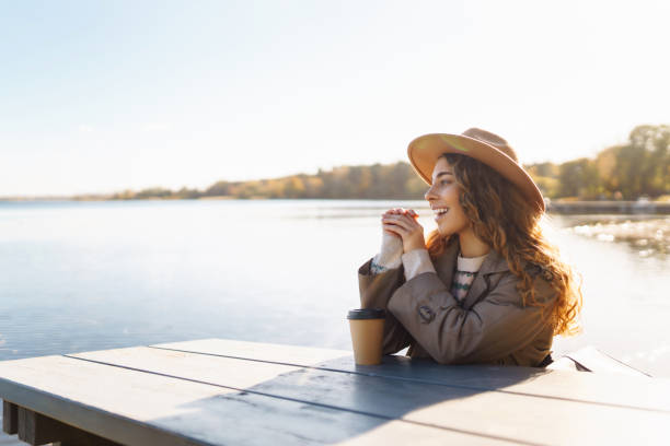 istock Young woman enjoying coffee outdoors while using smartphone in a sunny park during autumn. 2168024933