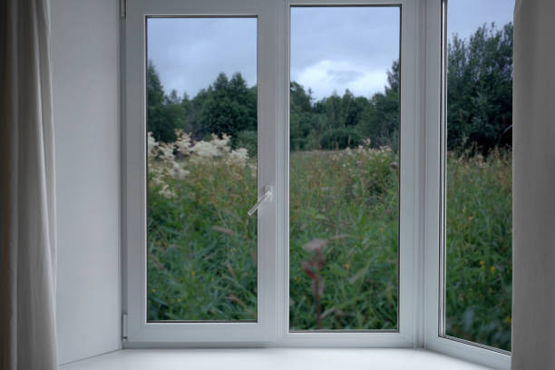 a beautifully crafted set of Georgian style white wooden bay windows with French doors. These are from an expensive new mansion house. The views are towards a frost garden outside. Three spot lights are mounted in the ceiling above.