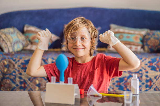 Kid boy doing chemical experiment at home. Child with protective glasses study using pipette dropping liquid to test tube, caucasian, biochemistry. chemistry class. home school concept.