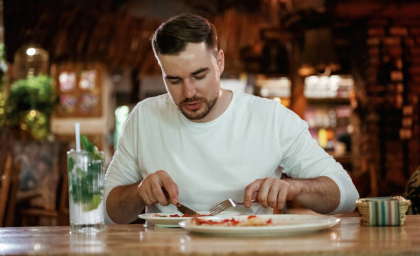 istock Man is sitting in the restaurant and eating a pizza 2168032656