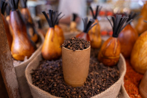 A pile of cinnamon is sitting in a brown container. The container is surrounded by other containers and bags