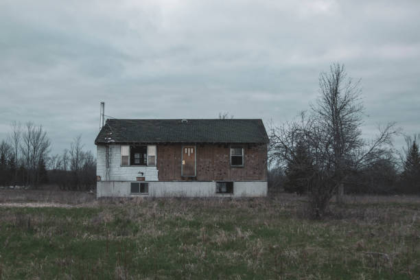 Abandoned, rundown decrepit house in an empty field.