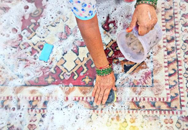 Happy Latin American couple unrolling a new carpet while moving home and smiling