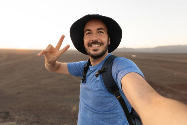 istock A happy man in a sun hat is smiling while taking a selfie in the desert landscape. 2168044807