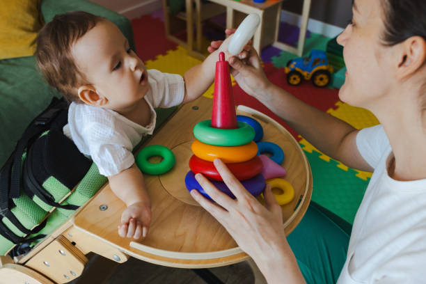 istock Handsome little boy with muscle weakness is actively participating in a rehabilitation session, focusing on tactile play with colorful stacking rings 2168049200