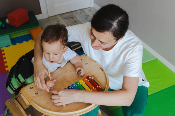 istock Handsome little boy with muscle weakness is actively involved in rehabilitation verticalization therapy, playing a xylophone with assistance in a cheerful environment 2168049202
