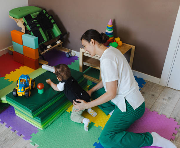 istock Young child with coordination disorders is practicing physical therapy with guidance in a colorful play area at home. Physical therapy for birth trauma rehabilitation 2168049238