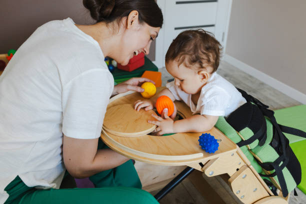 istock Little boy spends useful time standing in a verticalizer during physical therapy with a physiotherapist. Children's verticalizer 2168049244
