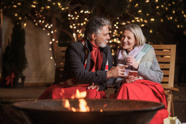 istock Smiling couple enjoying a warm beverage by the festive fire pit 2168051192