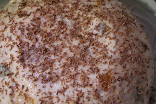 This dessert features a smooth, creamy surface generously adorned with delicate shavings of chocolate, creating an enticing visual and flavorful appeal.