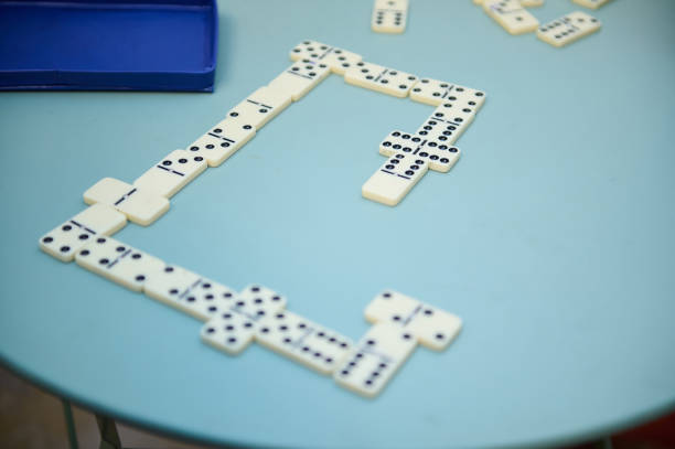 A game of dominoes in progress on a blue table, showing connected tiles. Perfect for concepts of leisure, strategy, and relaxation.