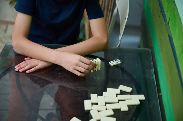 istock Child playing domino game at table showcasing concentration and leisure activity in a casual home setting. 2168059254
