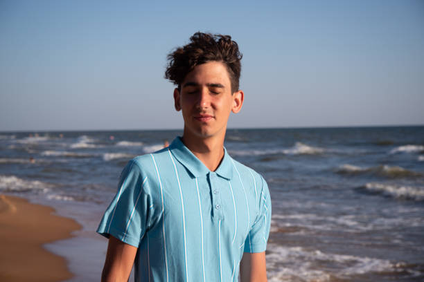 istock A young attractive guy is walking on the beach. 2168060253