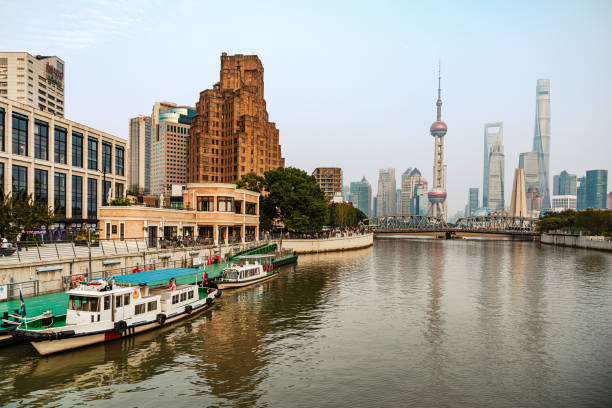 Beautiful image capturing Shanghai's skyline, featuring the Oriental Pearl Tower and historic architecture by the river. Perfect for showcasing modern cityscapes and urban beauty.