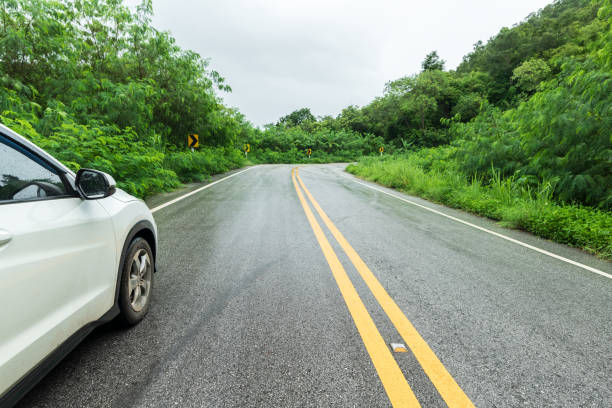 istock Wet asphalt road and side rear-view mirror on a car. 2168063121