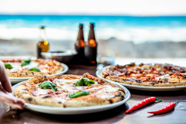 istock Three delicious pizzas served by the beach with a scenic ocean view. Fresh ingredients and chilled beverages complete the perfect seaside meal. 2168065791