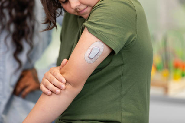 istock Boy winces while looking at new glucose monitor on arm 2168066201